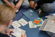 Bedruckte Karten liegen vor Schülerinnen auf dem Boden