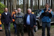 verschiedene Teilnehmer stehen auf einem Forstweg und hören den Ausführungen des Försters zu