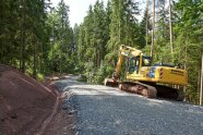 Ein Wegebagger steht auf einem neu gebauten Waldweg