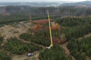 Luftbild von einem Waldgebiet, in dessen Zentrum ein Kran mit einer Hebebühne auf 37 Metern 