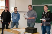Vier Männer stehen vor Tafel in einem Klassenzimmer