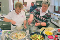 Zwei Frauen vor mehreren Töpfen am Herd